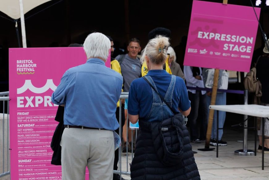 two people looking at a pink sign with their backs facing the camera